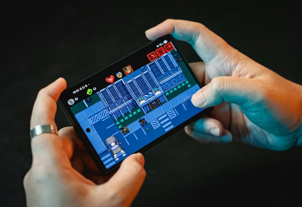 Tangan memainkan game di layar smartphone gaming