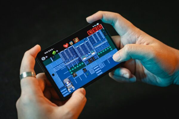 Tangan memainkan game di layar smartphone gaming